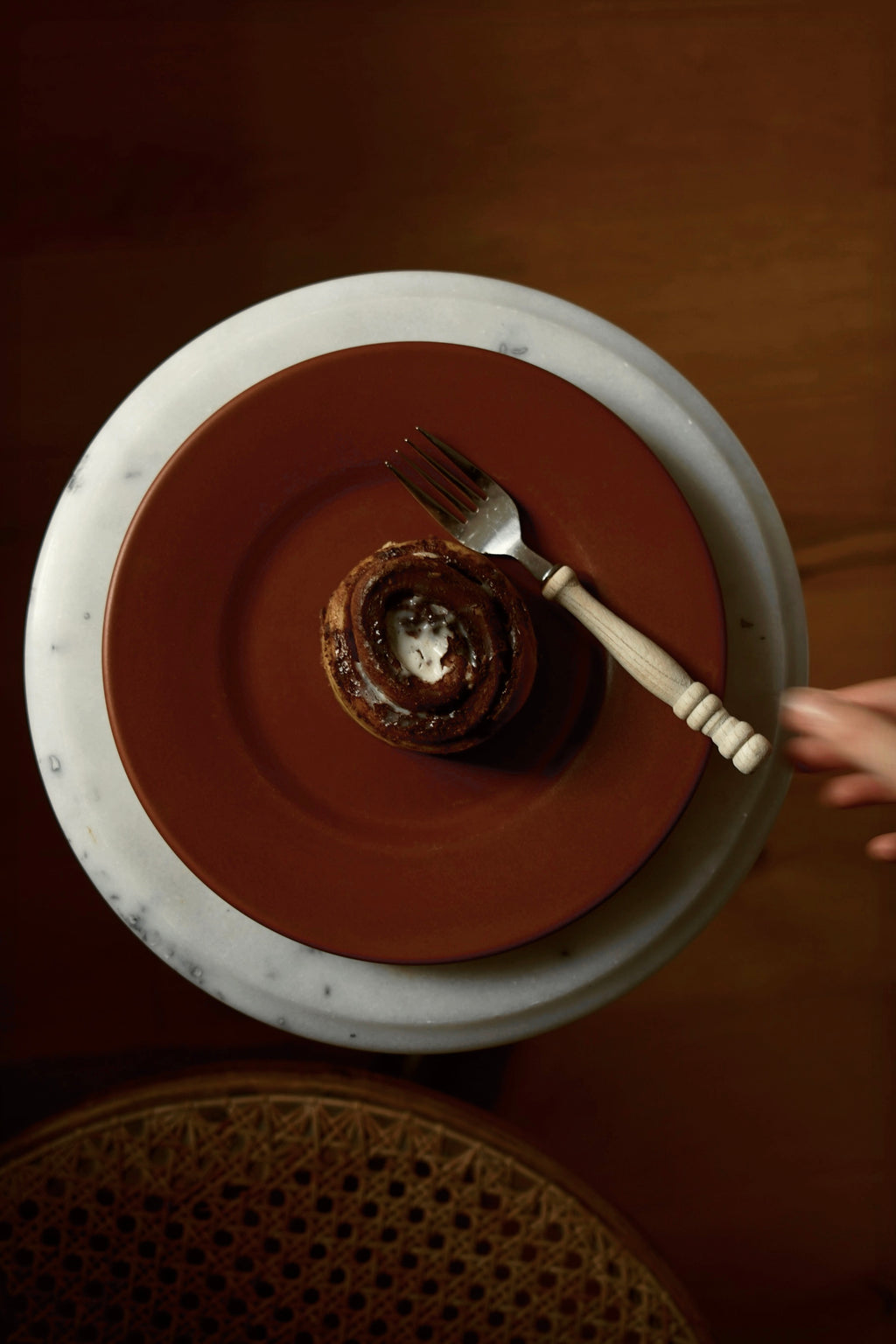 Roter Teller auf Mamortisch mit Zimtschnecke