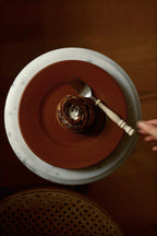 Roter Teller auf Mamortisch mit Zimtschnecke