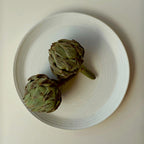 Weißer Servierteller aus Steingut mit zwei Artischocken