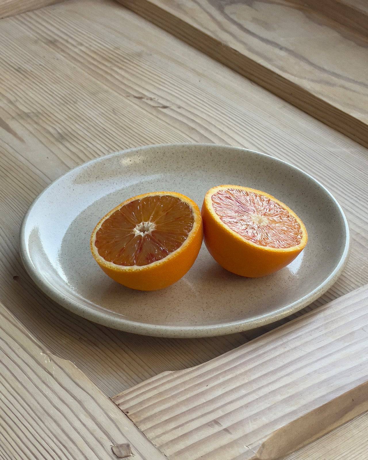 Keramikteller auf Holztisch mit aufgeschnittener Orange