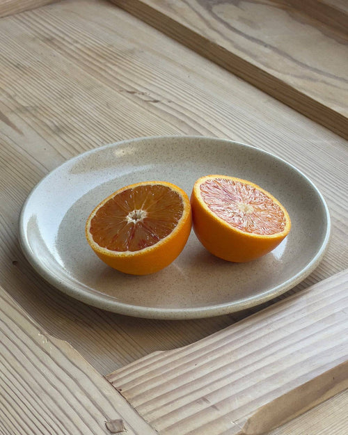 Keramikteller auf Holztisch mit aufgeschnittener Orange
