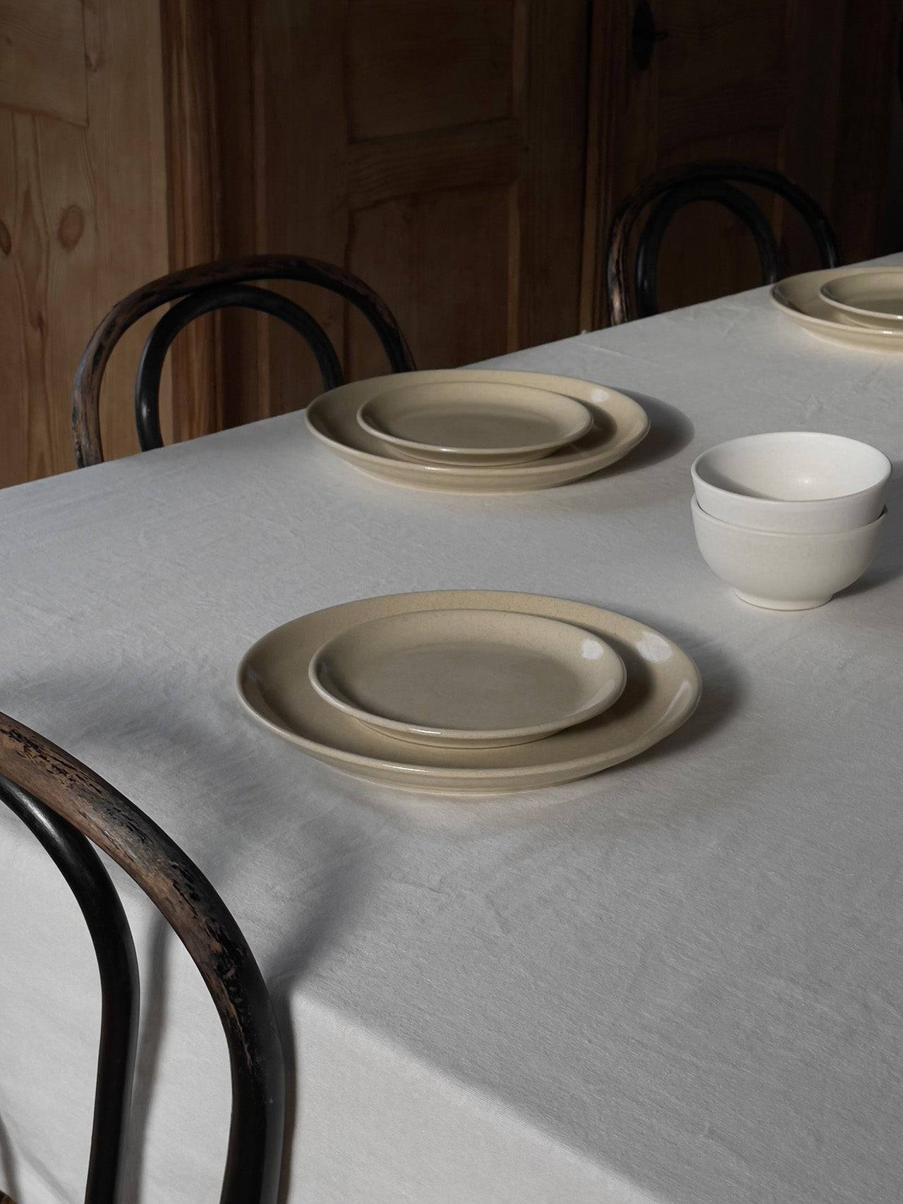Teller-Set aus einem großen und einem kleinen Keramikteller auf Tisch mit Leinentischdecke