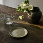Kleiner Teller Viana aus Steinzeug auf Holztisch mit Blumenvase und Glaskaraffe